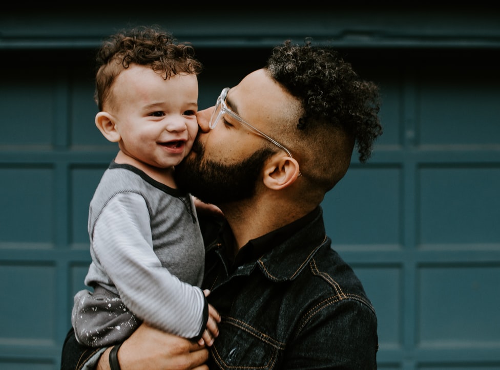 man holding and kissing child
