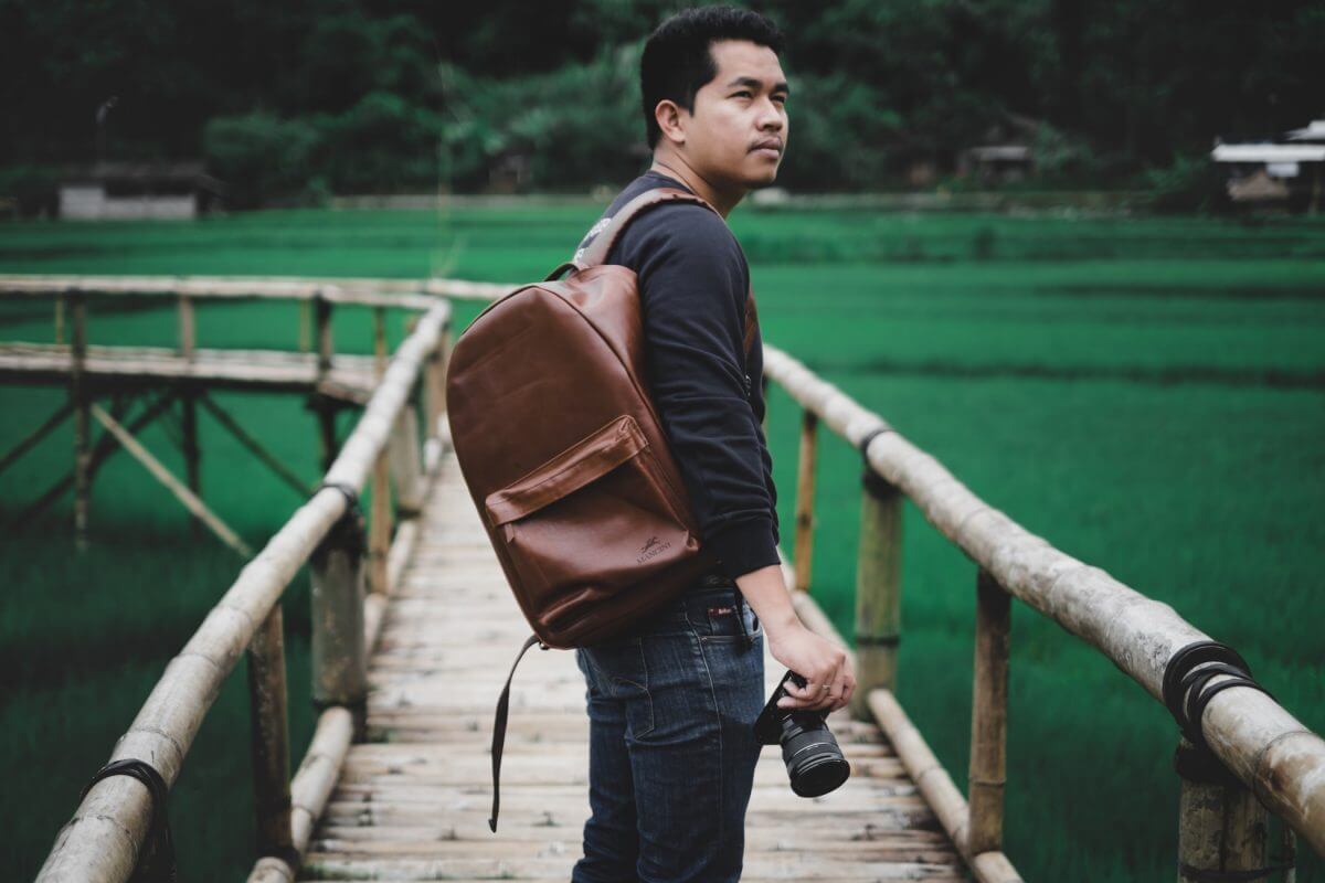 Man holding camera with leather backpack