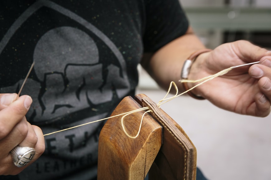 person stitching leather wallet