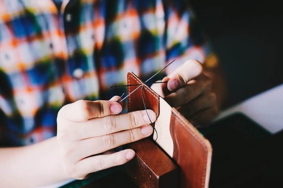 person making brown leather wallet