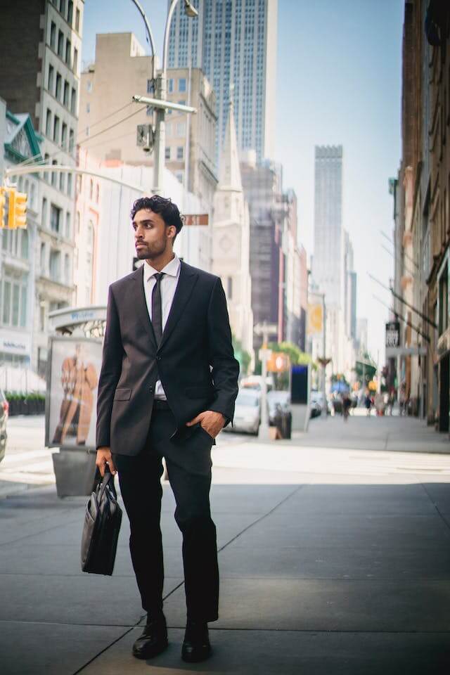 man in black suit with leather bag on sidewalk